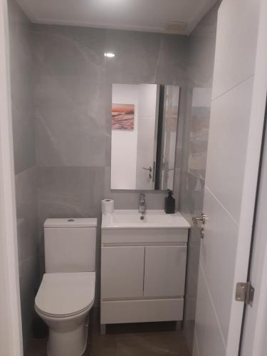 a white bathroom with a toilet and a sink at Plaza Caparica Hostel in Costa da Caparica