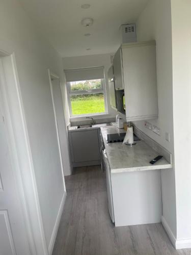 uma pequena cozinha com um lavatório e uma janela em Chalet with sea views em Ballyshannon