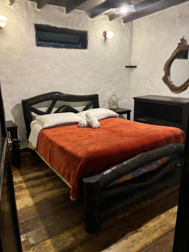 a bedroom with a large bed with a orange blanket at Finca Campestre La Adelita B&B in Salento