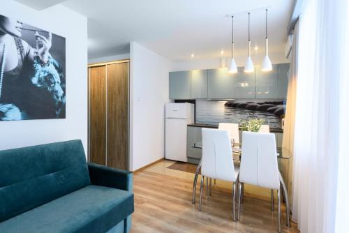 a kitchen and dining room with a table and white chairs at Pokoje, Noclegi, Apartamenty Dune Resort Łeba in Łeba
