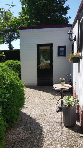 a small white shed with a table and a door at Chalet direkt an der Gracht mit eigenem Bootsanlegesteiger in Wervershoof