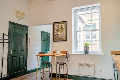 une cuisine avec des portes vertes, une table et deux tabourets dans l'établissement Guest Homes - Foregate Studio Apartment, à Worcester
