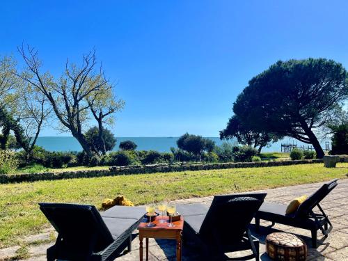 eine Terrasse mit Stühlen und einem Tisch mit Weingläsern in der Unterkunft Le petit Fauchon - Villa avec vue mer in Île dʼAix