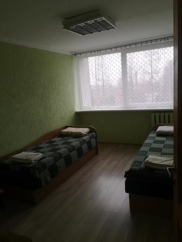 a room with two beds and two windows at Kambarių nuoma Žeimelyje in Žeimelis