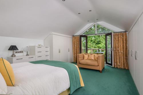 a bedroom with a bed and a chair and a window at The Gardeners Cottage, Hutton John is a luxurious cottage with hot tub 10 minutes from Lake Ullswater in Penruddock