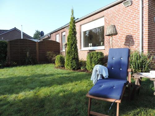 uma cadeira azul sentada na relva num quintal em Ferienhaus in Blandorf-Wichte mit Garten und Terrasse em Hage