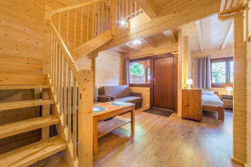 a living room with a staircase in a log cabin at Ośrodek Wypoczynkowy NA WYDMIE in Dziwnów