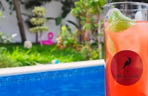a drink in a cup next to a swimming pool at Les Sons du Jardin Monastir in Monastir