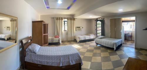 a room with two beds and a living room at Pousada MK TOUR in Pedra de Guaratiba