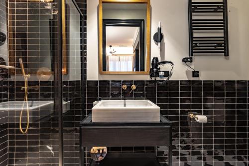 Baño de azulejos negros con lavabo y espejo en Old Town Apartments by Staynnapartments, en Bilbao