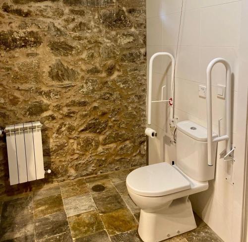 a bathroom with a toilet and a stone wall at Hotel Pazo de Bieite in Boimorto