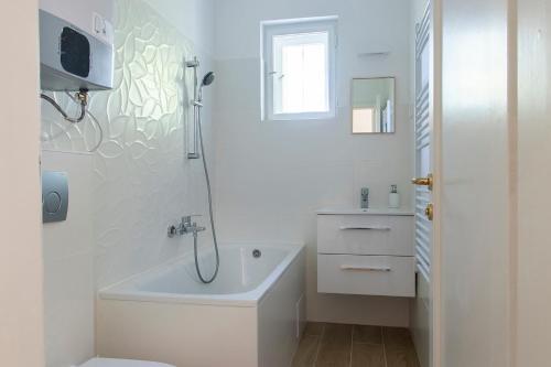 a white bathroom with a tub and a sink at Villa Keller in Balatonboglár
