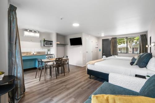 a bedroom with a bed and a table and a kitchen at Tasman Holiday Parks - Christchurch in Christchurch