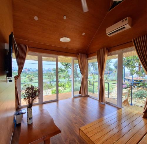 uma sala de estar com pisos em madeira e janelas grandes em Nhà bên hồ sen em Bao Loc