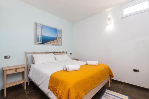 a bedroom with a bed with a yellow blanket at Sa Dommu e Mare in Santa Maria Navarrese