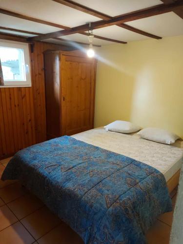 a bedroom with a bed with a blue comforter at chalet avec jacuzzi in Manhay