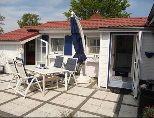 a patio with a table and an umbrella at Ferienhaus De Graaf mit einer sonnigen Terrasse und Garten IJsselmeer in Wervershoof