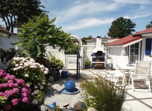 a backyard with a patio with a grill and flowers at Ferienhaus De Graaf mit einer sonnigen Terrasse und Garten IJsselmeer in Wervershoof