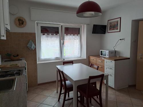 uma cozinha com uma mesa e cadeiras brancas e 2 janelas em Casa Vanna em Mezzano