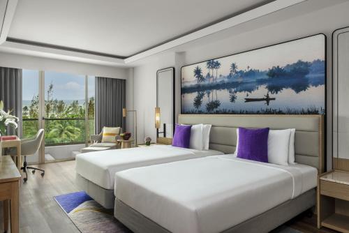 パナジにあるVivanta Goa, Miramarのホテルルーム 紫色の枕 ベッド2台付