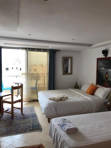 a bedroom with two beds and a table and a window at Les Bains de Mirleft in Mirleft