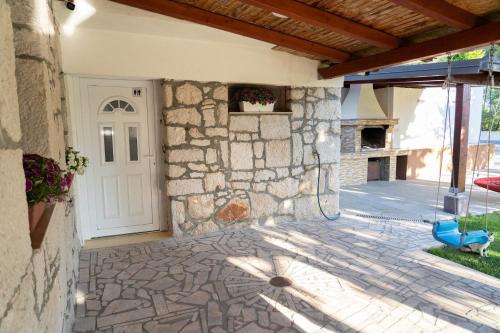 a building with a stone wall and a white door at Villa Kamena with Pool, Jacuzzi & Sauna in Grude
