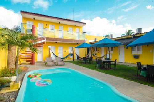 a swimming pool in front of a yellow house at Pousada Summer Beach by AFT in Porto De Galinhas