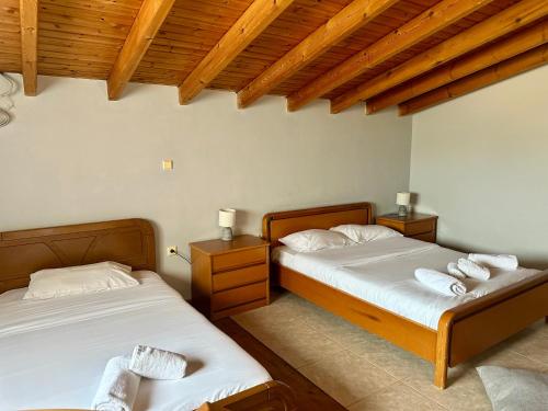 two beds in a bedroom with wooden ceilings at A&D Apartments in Porto Rafti