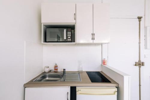 a small kitchen with a sink and a microwave at GuestReady - Radiance in comfort near Paris in Saint-Cloud