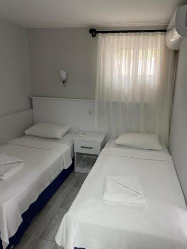 two beds in a small room with white walls at İZAN VİLLA BAKIŞ APARTMENTS in Bodrum City