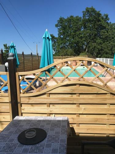 a wooden fence with umbrellas and a pool at Gîtes Le Mas du Vieux Chêne in Salavas