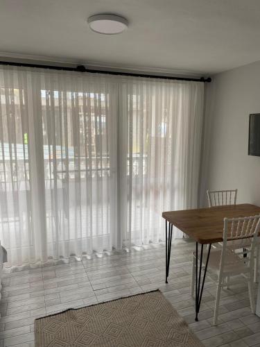 a room with a table and a large window with white curtains at İZAN VİLLA BAKIŞ APARTMENTS in Bodrum City