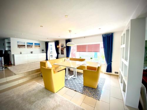 a living room with a table and yellow chairs at Ferienhaus direkt am See in Wervershoof