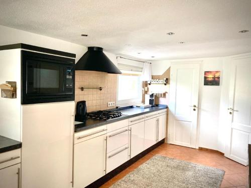 a kitchen with white cabinets and a stove top oven at Ferienhaus direkt am See in Wervershoof