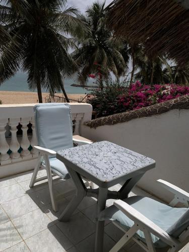 a table and a chair on a patio with the beach at West AFRICAN BEACH in Sali Nianiaral
