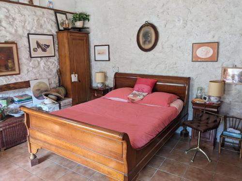sypialnia z drewnianym łóżkiem z czerwoną kołdrą w obiekcie Les Chaises w mieście Raizeux