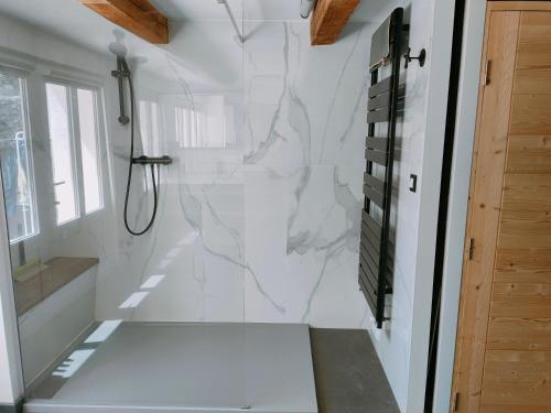 a bathroom with white marble walls and a shower at MAISON DE CARACTERE POUR 6 PERS AVEC PISCINE in Agde
