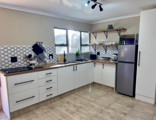 a kitchen with white cabinets and a stainless steel refrigerator at Sugar Plum Rest in Polokwane
