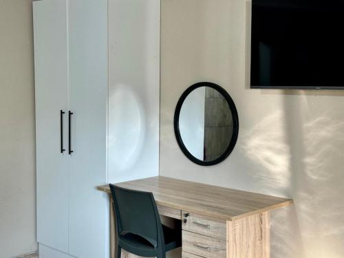 a mirror on a wall next to a desk with a chair at Sugar Plum Rest in Polokwane
