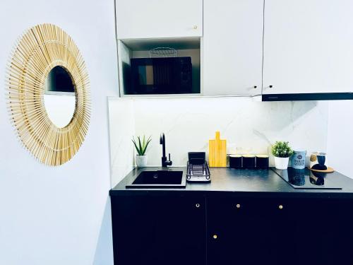 a kitchen with a black counter and a mirror at Olivia Apartments - Słoneczny apartament w centrum Warszawy, Plac Unii Lubelskiej, Łazienki Królewskie, Pole Mokotowskie - 24h check-in in Warsaw