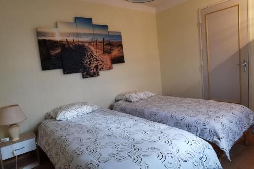 une chambre avec deux lits et un tableau au mur dans l'établissement Plain pied calme parking privé 5 lits 1 lit bébé proximité Metz, à Woippy