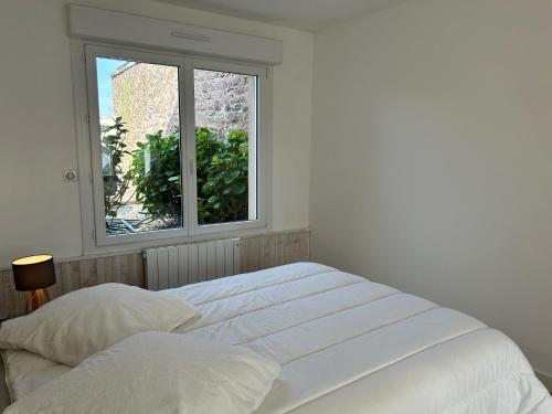 a white bedroom with a bed and a window at 302 - Bel appartement rénové en centre de FREHEL in Frehel