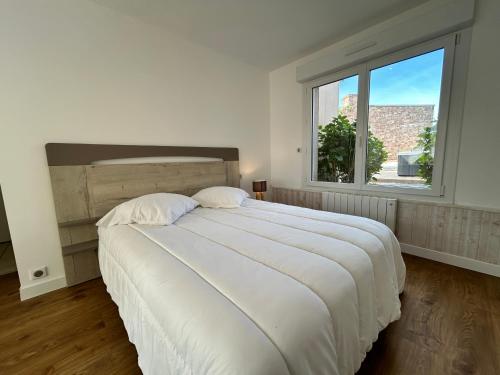 a bedroom with a large white bed with a window at 302 - Bel appartement rénové en centre de FREHEL in Frehel