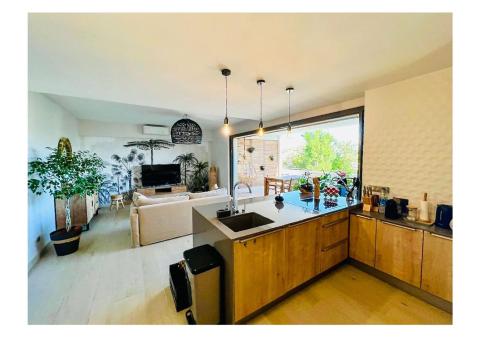 a kitchen with a sink and a living room at Escapade romantique Baie Nettlé in Baie Nettle