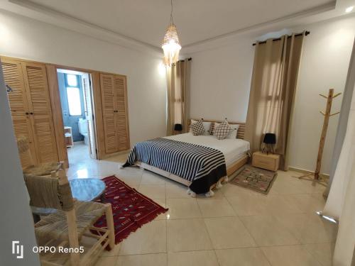 a bedroom with a bed and a chair in it at Villa Tazerzit comfort et hospitalité in Essaouira