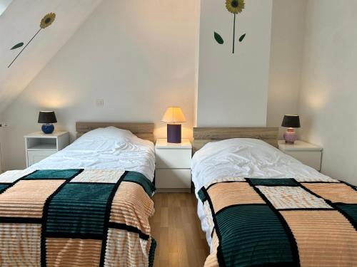 two beds in a bedroom with two lamps on the sides at 314 - Maison 4p à moins d'un km de l'Anse du Croc in Frehel