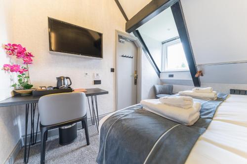 a room with a bed and a desk and a tv at The Log House in Ambleside