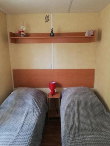 une chambre avec deux lits et une tasse rouge entre eux dans l'établissement CAMPING 3* / GORGES DU VERDON / POUR 2 PERS/ LAVANDE / ACTIVITÉS/A 2 MN DU LAC DE STE CROIXI, à Sainte-Croix-de-Verdon