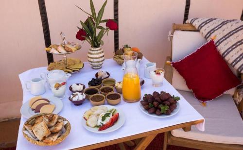 einen Tisch mit Frühstückszutaten und Orangensaft darauf in der Unterkunft riad luz merzouga in Merzouga