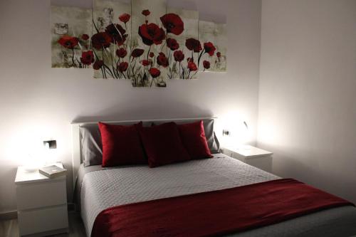 a bedroom with a bed with red pillows and paintings on the wall at La Luna Blu Malpensa appartamento Papaveri in Somma Lombardo